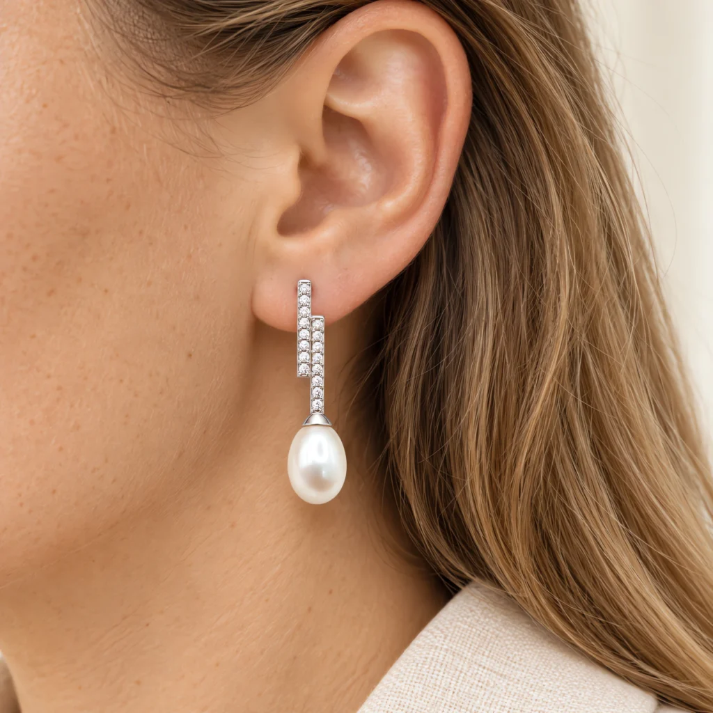 Model wearing geometric silver and teardrop freshwater pearl drop earrings showing scale and drape