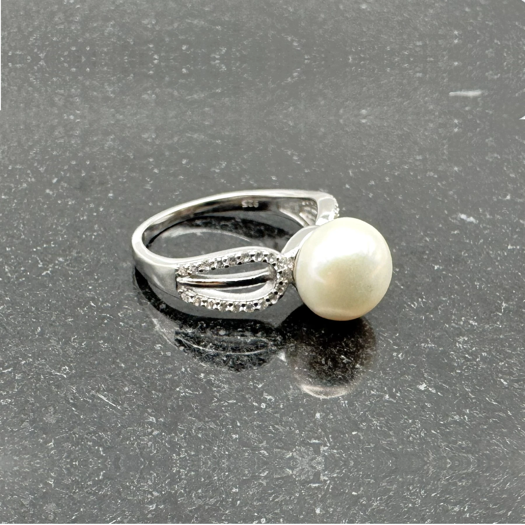Split-shank white freshwater pearl and CZ pavé ring on black marble